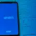 Smartphone exibindo tela do ENEM apoiado sobre livro aberto de matemática com questões