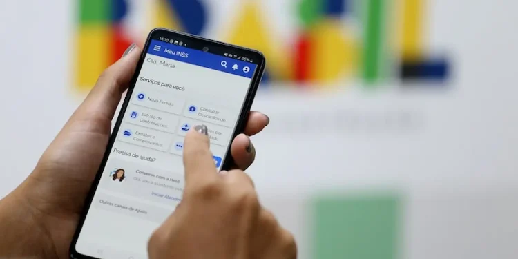 Segurado acessa aplicativo Meu INSS no celular para verificar descontos no benefício previdenciário.