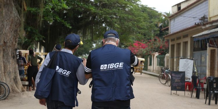 Dois agentes do IBGE de costas caminhando em área urbana durante trabalho de campo