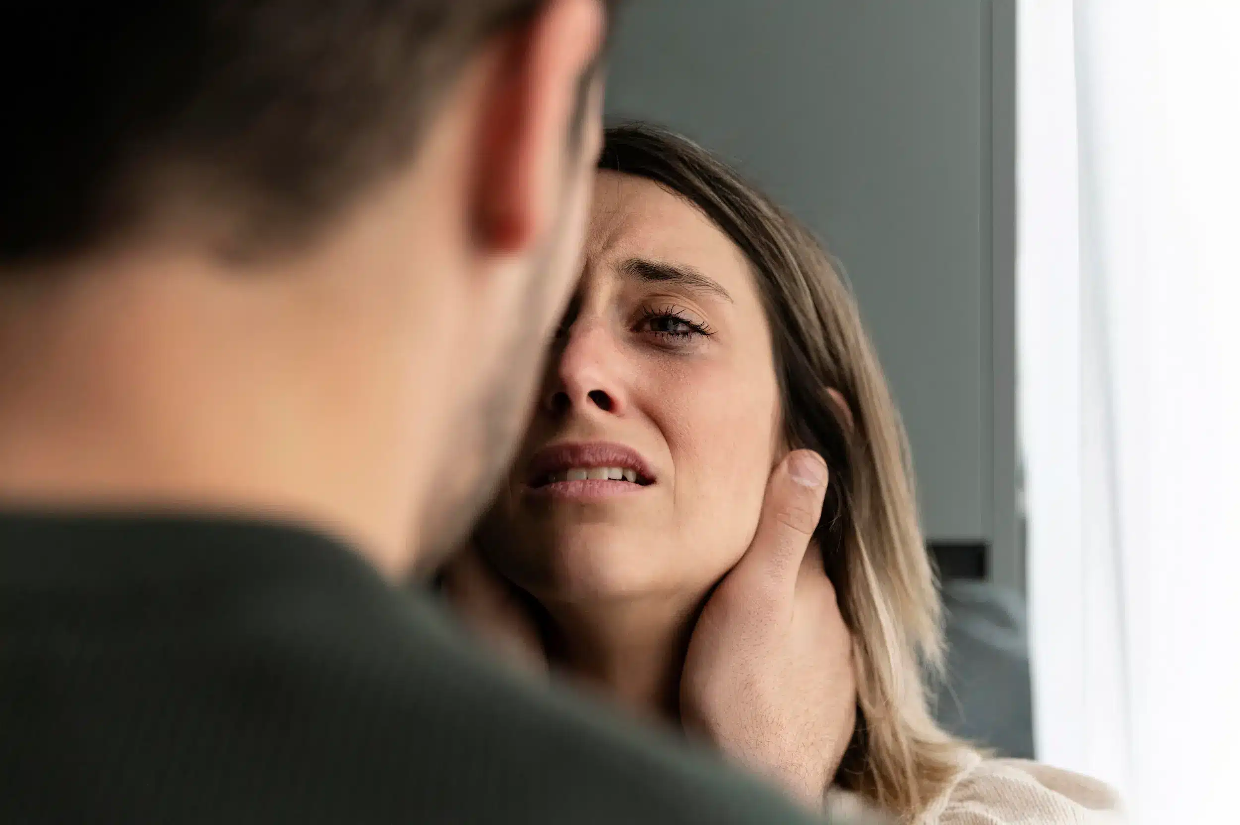 Imagem de uma pessoa em um confronto emocional com um narcisista. Ela parece angustiada e está sendo fisicamente tocada de forma manipulativa durante a discussão.