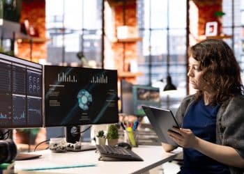 Profissional de IA analisando dashboards e dados em monitores representando funções de inteligência artificial nas empresas
