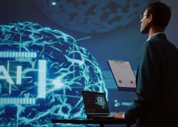 Especialista em tecnologia analisando dados de inteligência artificial em notebook com projeção digital futurista ao fundo.