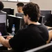 Jovens estudantes em laboratório de informática com notebooks e computadores realizando atividades práticas de cibersegurança no programa Hackers do Bem, iniciativa gratuita da Rede Nacional de Ensino e Pesquisa com mais de 25 mil vagas abertas.