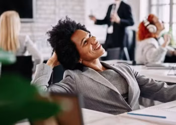 Mulher sorrindo e feliz em ambiente de trabalho, ilustrando o conceito de felicidade no trabalho abordado na regra dos três metros.