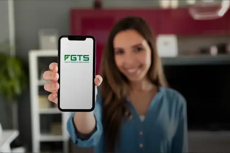 Mulher sorridente segura celular com tela do FGTS em destaque no centro