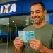 Trabalhador segura notas de real em frente à Caixa Econômica Federal, representando a solicitação do saque de até R$ 6.220 do FGTS.
