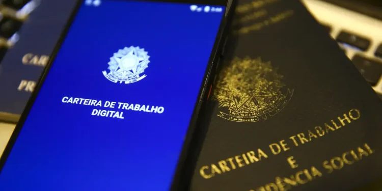 Carteira de Trabalho física e digital ao lado de teclado, representando o prazo de pagamento do salário garantido pela CLT aos trabalhadores brasileiros