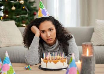 Jovem triste com bolo de aniversário.