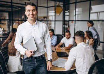 Profissional sorridente lidera reunião de equipe em escritório moderno.