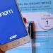 Celular com logo do Enem e caderno azul do exame, ilustrando o prazo para solicitar isenção da taxa de inscrição.