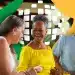 Três idosos sorrindo em confraternização ao ar livre com cores vibrantes.
