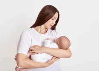 Mãe segura bebê recém-nascido em momento de conexão.