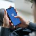 Pessoa segurando um smartphone com o logotipo do LinkedIn aberto na tela, em um ambiente de escritório.