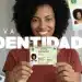 Mulher negra sorrindo segurando novo RG brasileiro com texto Nova Identidade em destaque