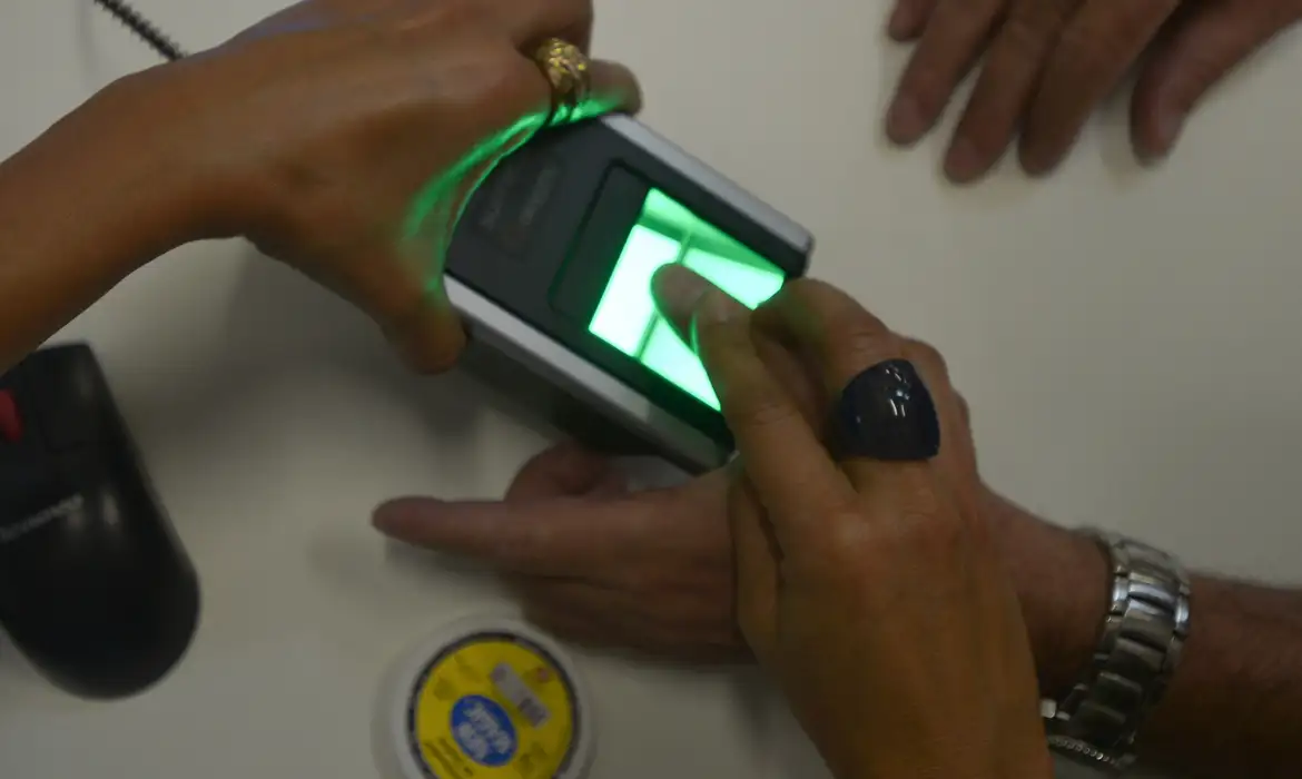 Leitor biométrico captura digital de cidadão para emissão da Carteira de Identidade Nacional, exigência para beneficiários do Bolsa Família, Pé-de-Meia e INSS