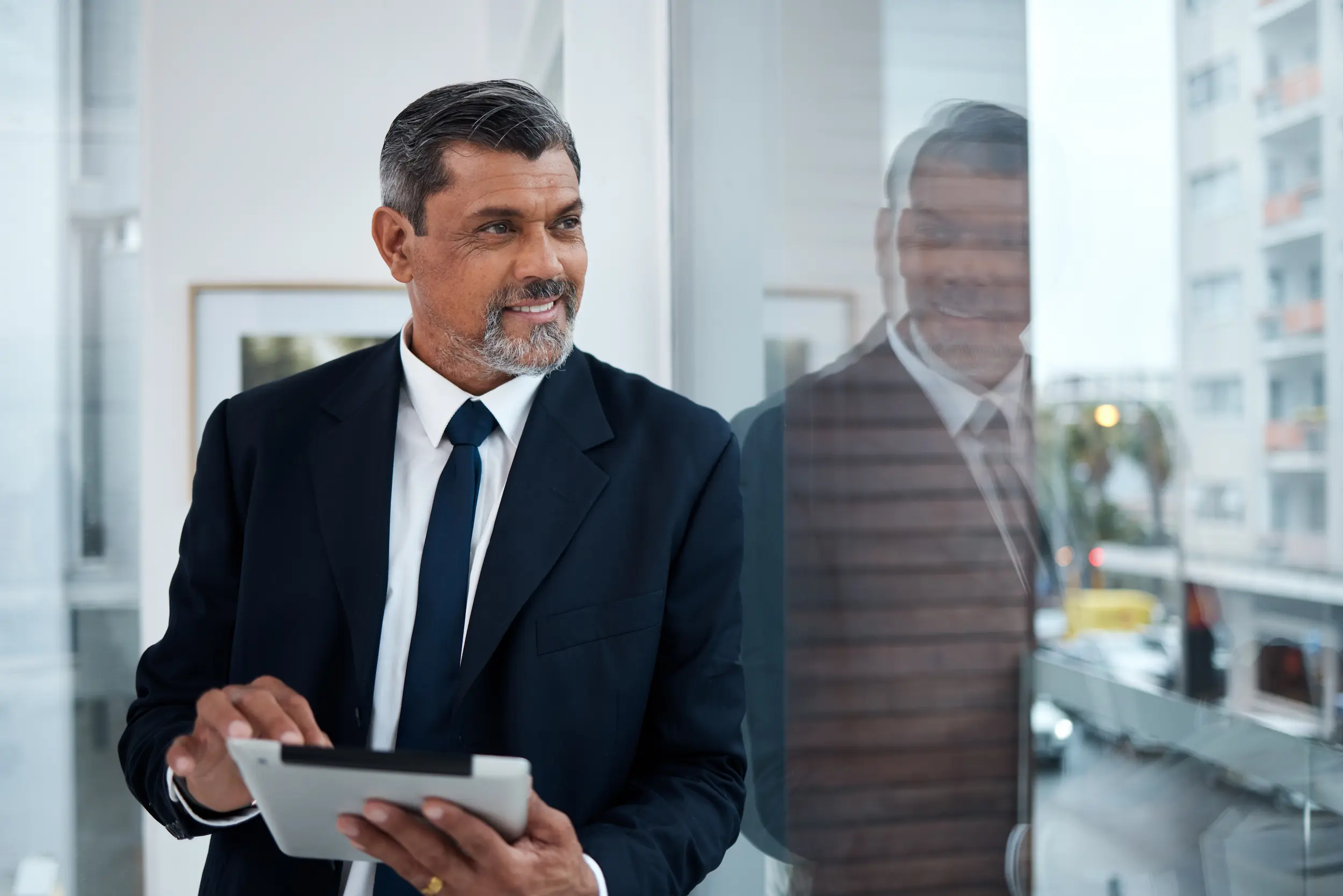 Executivo em ambiente corporativo utilizando tablet representando cargos de direção bem remunerados em Portugal.