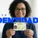 Mulher sorrindo segura a nova carteira de identidade nacional durante campanha de emissão gratuita em cartórios.