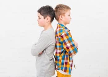 Dois irmãos crianças em posição de costas demonstrando rivalidade infantil causada por comparações familiares.