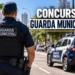 Guarda Municipal de costas em rua urbana ao lado de viatura, representando o concurso.