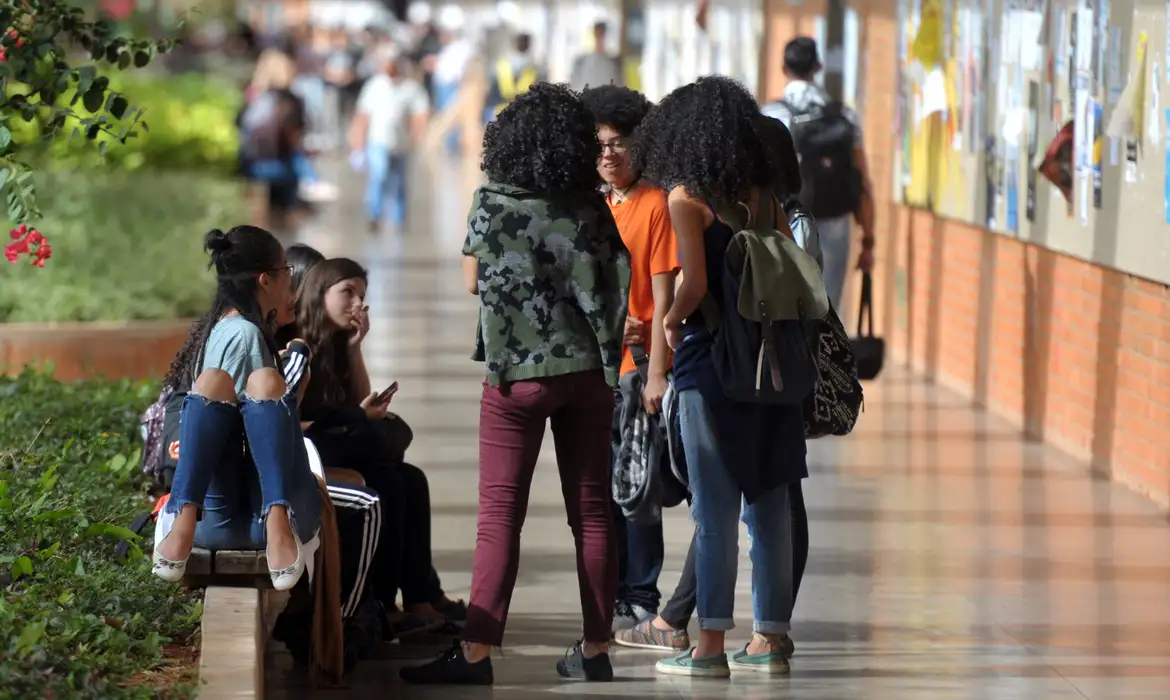 Grupo de estudantes universitários conversando no corredor de um campus, em alusão aos cursos e profissões promissoras no Brasil.