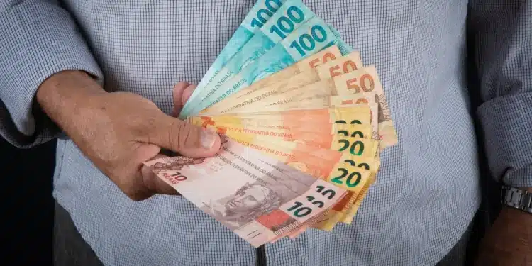 Notas de dinheiro com valores de R$ 10, R$20, R$50 e R$100, representando o 13º salário do INSS para aposentados e pensionistas que recebem acima de um salário mínimo.