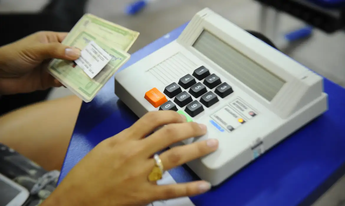 Pessoa utiliza equipamento de atendimento eleitoral durante procedimento relacionado ao título de eleitor.