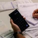 Consumidor fazendo contas em calculadora do celular cercado de faturas de energia elétrica com suspeita de empréstimo indevido