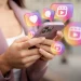 Pessoa segurando smartphone com ícones de redes sociais enquanto reflete antes de postar uma indireta online.