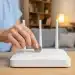 Pessoa colocando moeda sobre roteador Wi-Fi em casa para tentar melhorar o sinal de internet