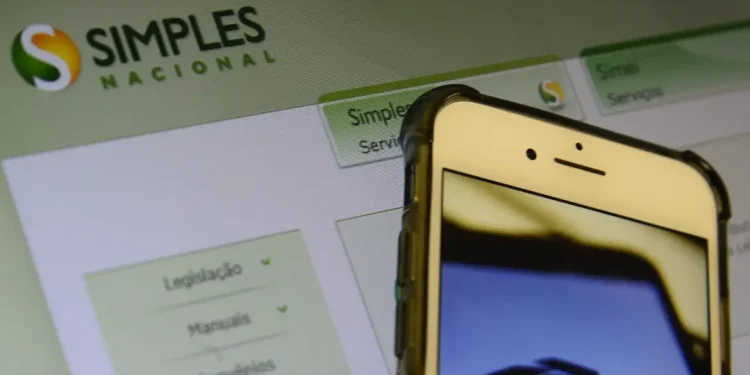 Tela com portal do Simples Nacional e celular com logo da Receita Federal representando as novas regras para microempresas
