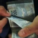 Mãos manuseiam um maço de cédulas de R$ 100 do real, ilustrando o pagamento do abono salarial PIS/Pasep aos trabalhadores beneficiários.