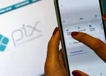 Mão feminina toca tela de celular no menu Pix com opções pagar, ler QR code e receber
