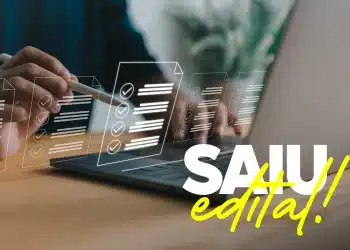 Mão usando caneta stylus em notebook com ícones de documentos e checklists e texto Saiu Edital em destaque
