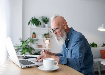 Homem maduro trabalhando no notebook em casa, representando renda extra online após os 50 anos.