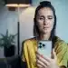 Mulher usando smartphone com reconhecimento facial, processo de verificação digital de identidade.