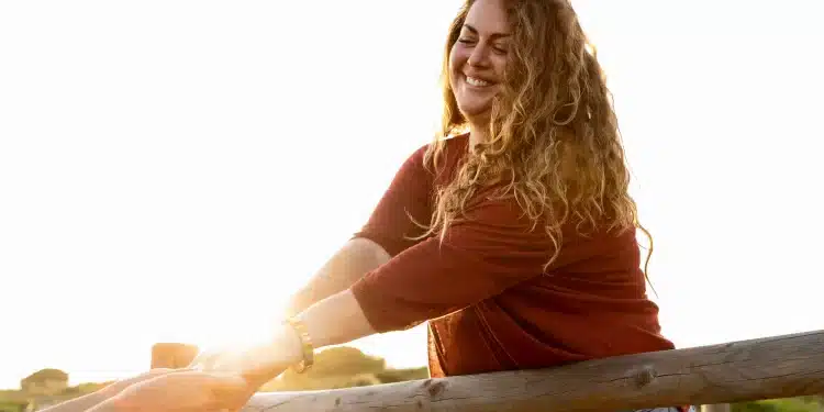 Mulher sorrindo ao ar livre durante um momento tranquilo de solitude e bem-estar emocional.