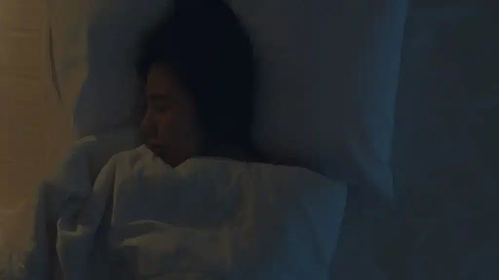 Mulher dormindo em um ambiente escuro, representando a importância do sono sem luz.