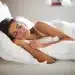 Mulher dormindo confortavelmente na cama representando a importância das horas ideais de sono por idade
