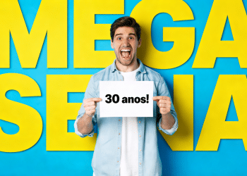 Homem jovem comemora segurando placa "R$ 150 milhões" com fundo azul e amarelo escrito "MEGA-SENA".