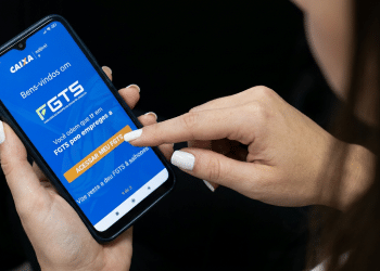 Trabalhadora acessa app oficial do FGTS da Caixa pelo celular.