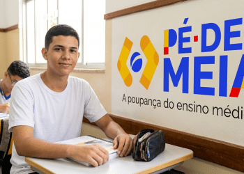 Jovem ao lado da logo do programa Pé-de-Meia.