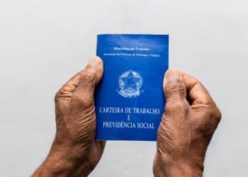 Mãos segurando uma carteira de trabalho.