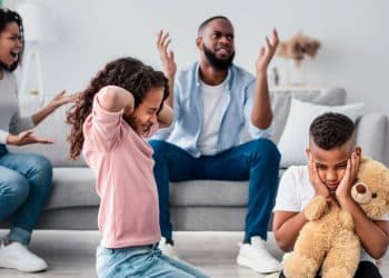 Crianças sofrem com conflito familiar enquanto pais discutem.