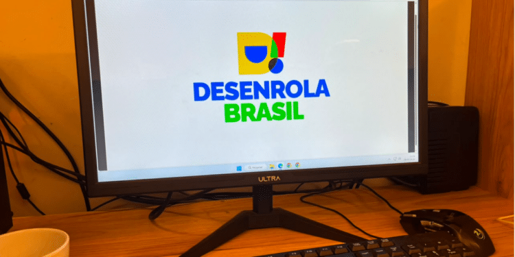Logo do Desenrola Brasil exibido em tela de computador em ambiente de trabalho.