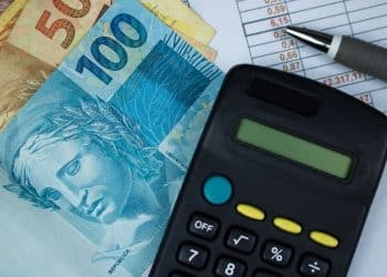 Cédulas de real brasileiro com calculadora e planilha financeira.