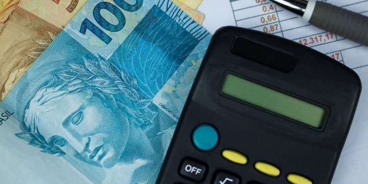 Cédulas de real brasileiro com calculadora e planilha financeira.