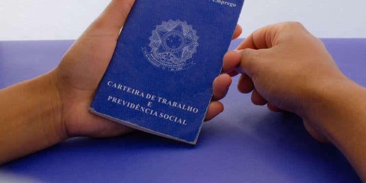 Carteira de Trabalho física do Brasil em mãos de trabalhador.