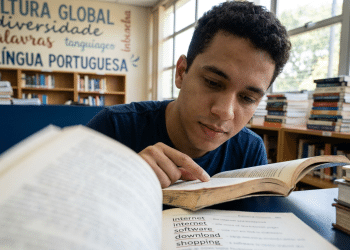 Jovem estuda língua portuguesa em biblioteca escolar.