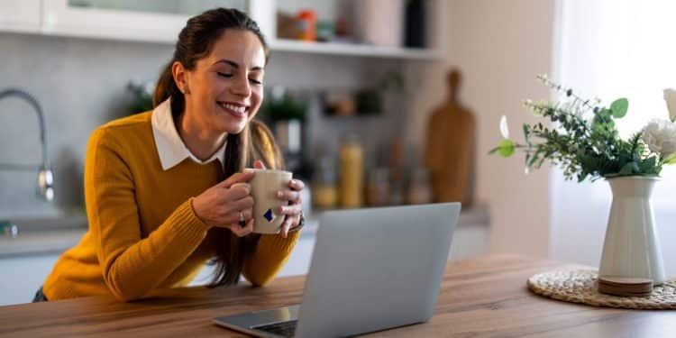 Mulher sorrindo enquanto olha para notebook.