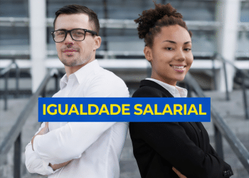 Homem de camisa branca e óculos e mulher negra de blazer preto, lado a lado, com faixa azul escrito "Igualdade Salarial".